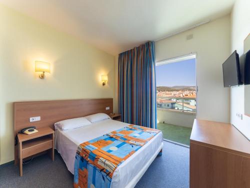 a hotel room with a bed and a large window at Hotel Natura Park in Comarruga