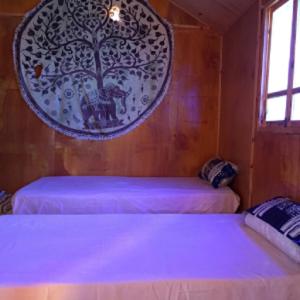 a bedroom with two beds and a tree on the wall at La Basha Camp in Dahab