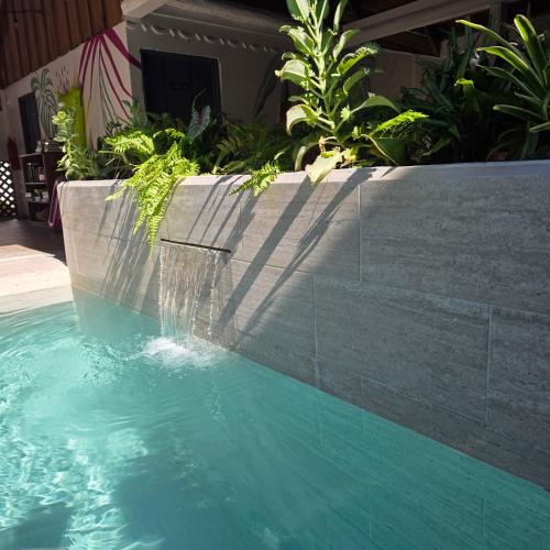 a swimming pool with a waterfall in a garden at La Rana De Cahuita in Cahuita