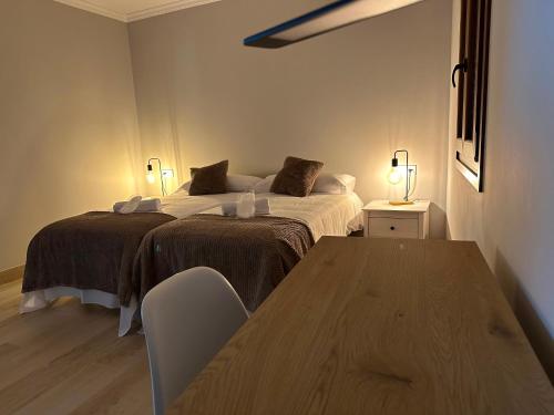 a bedroom with two beds and a wooden table at Pensión Eirín VI in Caldas de Reis