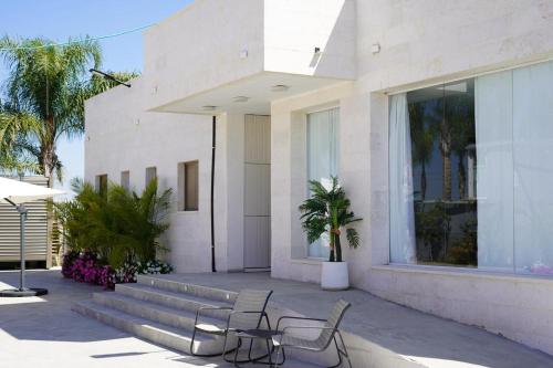 a building with two chairs and a table in front of it at אחוזת החושן - וילה מהממת עם בריכה פרטית in Tirosh