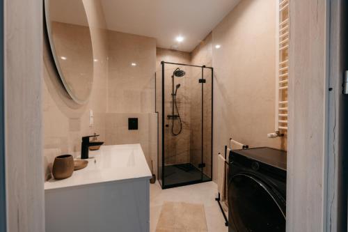 a bathroom with a shower and a sink and a washing machine at Panorama Silva in Augustów