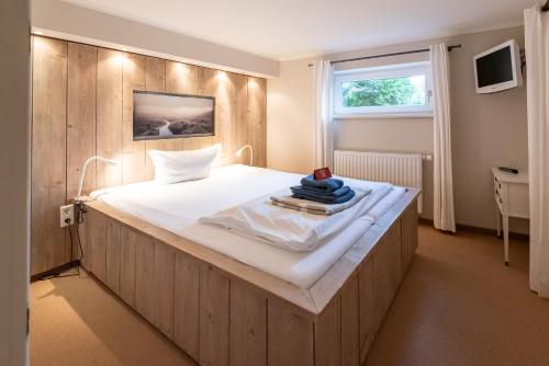 a bedroom with a large white bed with a window at Haus Strandkind in Sylt