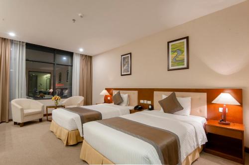 a hotel room with two beds and a table and chairs at Muong Thanh Grand Lao Cai Hotel in Lao Cai