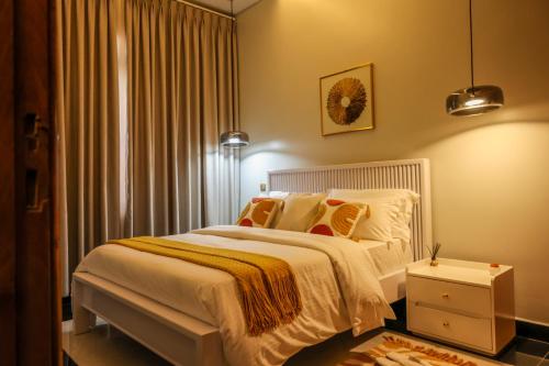 a bedroom with a bed with white sheets and orange pillows at Ruts Golden Homes in Kampala