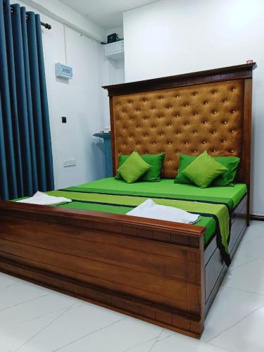 a wooden bed with green pillows in a room at Khs resort in Gelioya