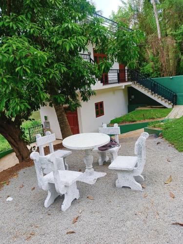 a white table and chairs sitting next to a tree at Khs resort in Gelioya