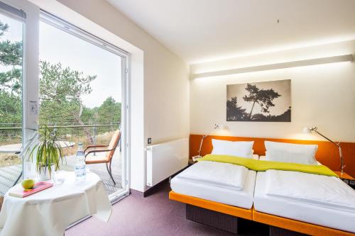 a bedroom with a bed and a balcony at Hotel Windschur in Sankt Peter-Ording