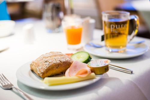 a plate of food with a sandwich and a glass of beer at Hotel Windschur in Sankt Peter-Ording