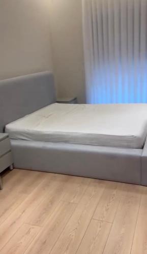 a bed sitting in a room with a wooden floor at Aura Stay Apartment in Tirana