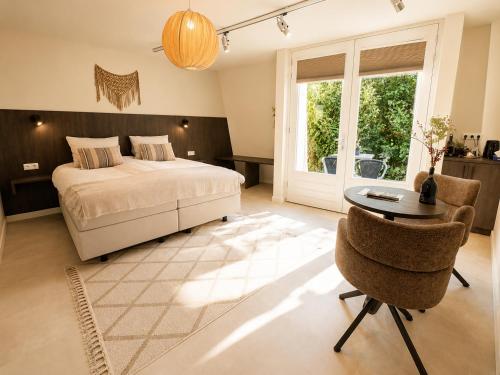 a bedroom with a bed and a table and a chair at De Meuleberg Boutique Suites in Melick