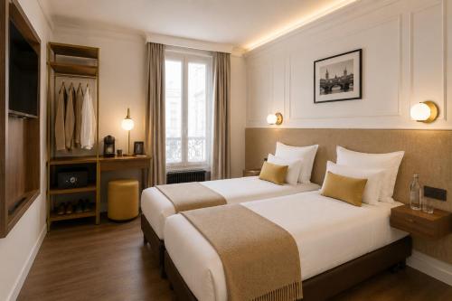 a hotel room with two beds and a window at Hôtel Beauvoisin in Paris