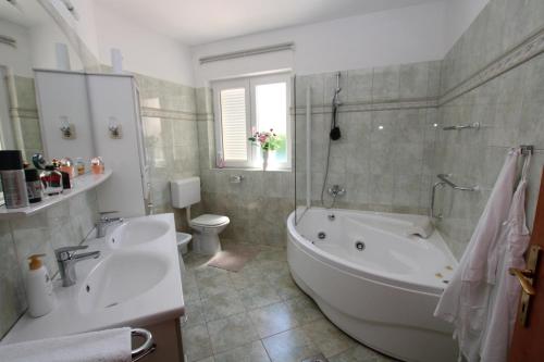 a bathroom with a tub and a toilet and a sink at Elegant Villa Hariz near Poreč - Fully AC & Large Pool in Gedići