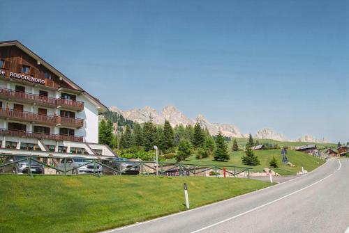 a hotel on the side of a road with mountains in the background at Residence Rododendro in Passo San Pellegrino