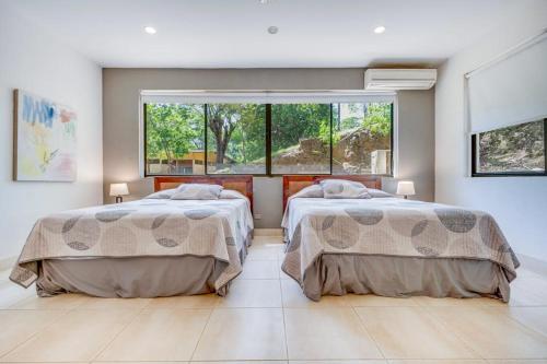 two beds in a room with a large window at Casa Carmen in Potrero