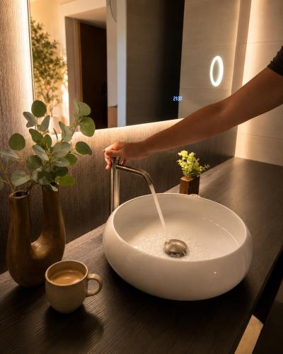 a person is pouring water into a white sink at De Meuleberg Boutique Suites in Melick