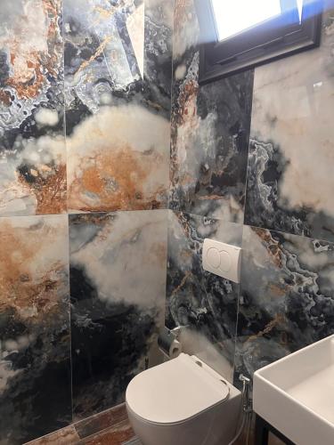 a bathroom with a toilet and a marble wall at Escape by Ambelas in Himare