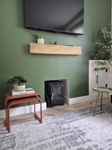 a living room with a fireplace and a green wall at Park House by Tŷ SA in Aberdare