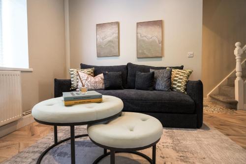 a living room with a couch and a table and two stools at Park House by Tŷ SA in Aberdare