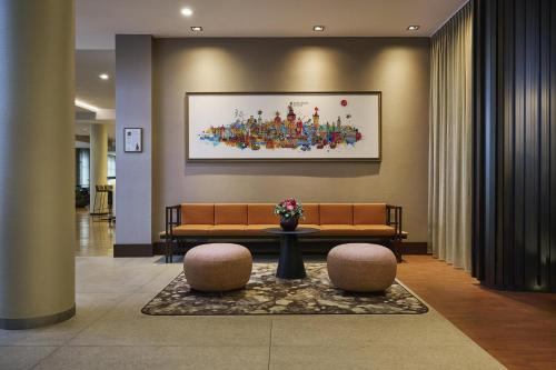 a lobby with a couch and two stools at NH Collection Nürnberg City in Nuremberg