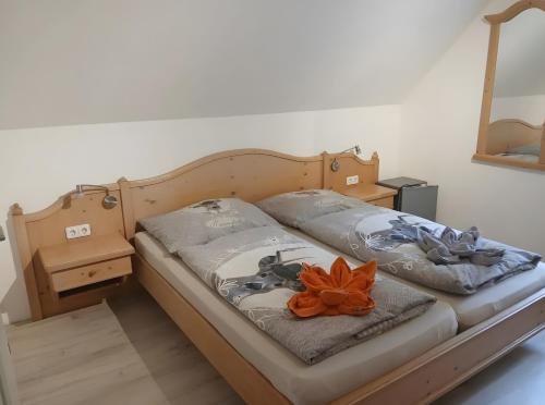 a bed with two pillows and an orange flower on it at Plösch Hof in Weinberg