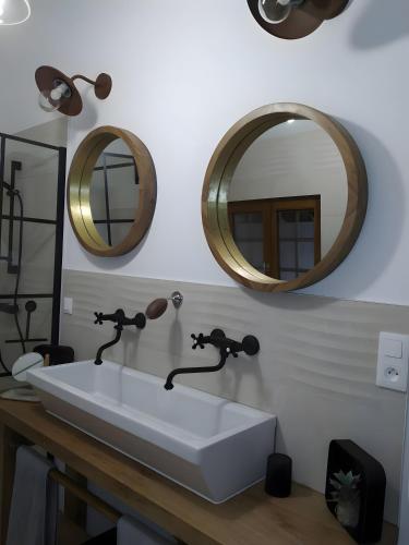 a bathroom with a white sink and two mirrors at Chambre - A La Maison Du Bonheur in Lanty-sur-Aube