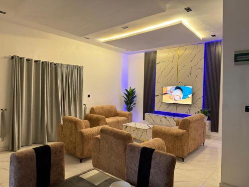 a living room with chairs and a couch and a tv at Esthella Property in Ijaiye