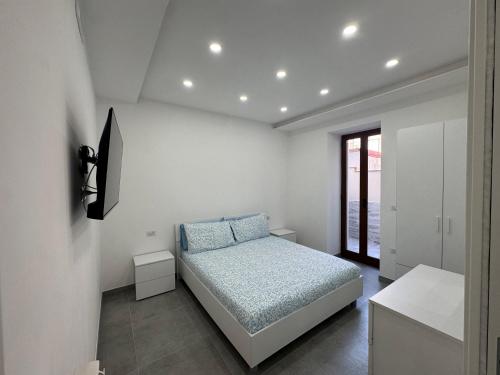 a white bedroom with a bed and a window at La dimora dei Giglianti in Brusciano