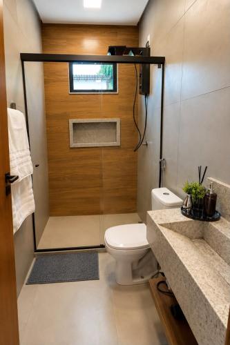 a bathroom with a toilet and a wooden door at Chalé 1 - Vivendas do Caparaó in Pedra Menina