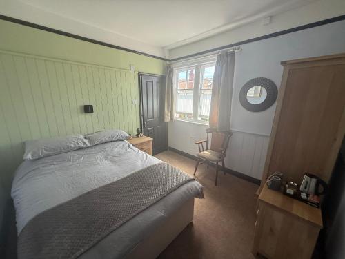 a bedroom with a bed and a chair and a window at The Fox Inn in Steventon