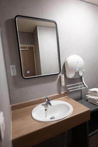 a bathroom with a sink and a mirror at L'Auberg'ine - Maison Glenn Anna in Sainte Anne d'Auray
