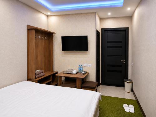 a bedroom with a bed and a table and a tv at Zamin Hotel in Shahrisabz