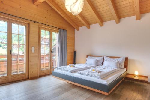 a bedroom with a large bed in a room with wooden ceilings at Apartment Bränderli - GRIWA RENT AG in Grindelwald