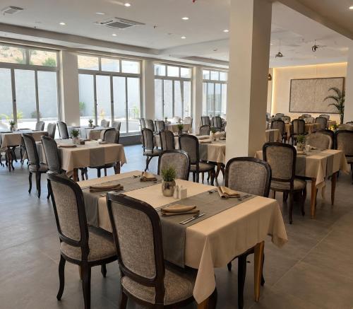 ein Esszimmer mit Tischen, Stühlen und Fenstern in der Unterkunft Unipark Hotel in Kurna