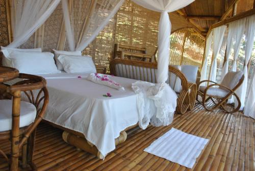 a bedroom with a bed and a table and chairs at Le Caveau de lemuriens in Nosy Be