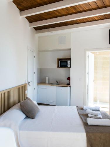 a white bedroom with a bed and a kitchen at A Calexa Sarria nº3 in Sarria
