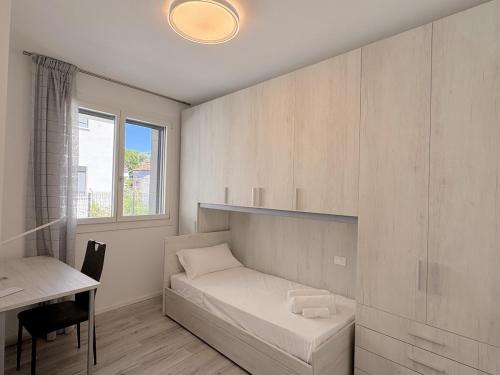 a bedroom with a bed and a desk and a window at golf time apartment - Lido di Venezia in Venice
