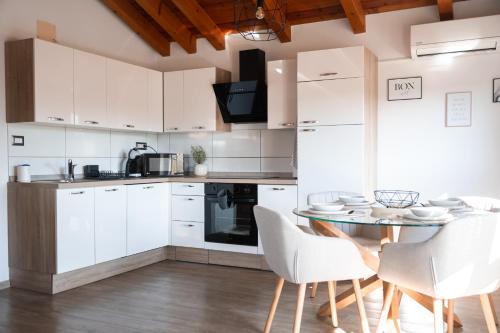 a kitchen with white cabinets and a table and chairs at I&R Apartma in Hrpelje