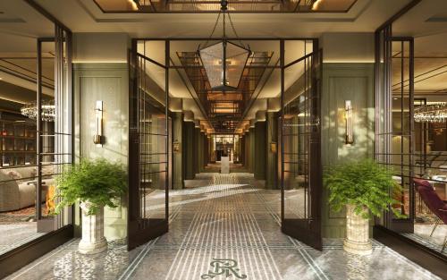 a hallway in a building with glass doors and plants at The St. Regis London in London