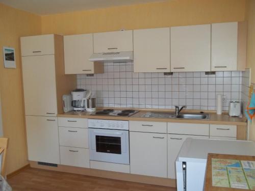 a kitchen with white cabinets and a sink at Ankerplatz H-7 in Butjadingen