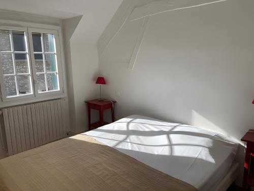a bedroom with a white bed with a window at Les Logis de la Vaucouleurs in Rosay
