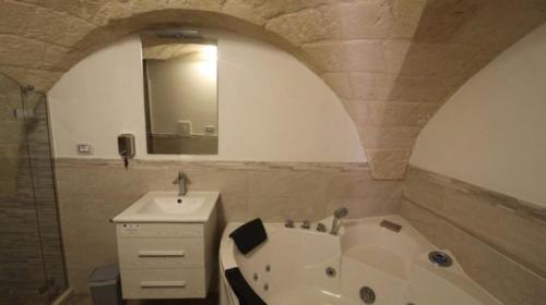 a bathroom with a tub and a sink and a mirror at Mastropaolo42 Luxury B&B in Grottaglie