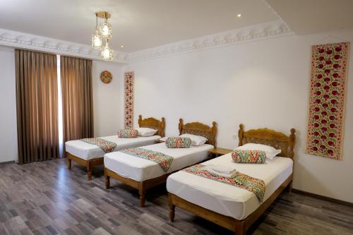 a room with three beds and a chandelier at Mashkobi Buxoro in Bukhara