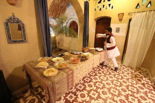 una mujer de pie junto a una mesa llena de comida en Scorpion House Luxor, en Luxor