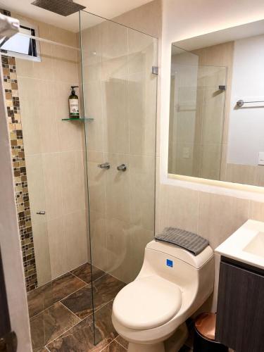 a bathroom with a toilet and a glass shower at Casa Tangara Café y Hospedaje in Medellín