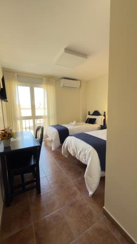a bedroom with two beds and a table and a desk at Hostal Valderas in Valderas