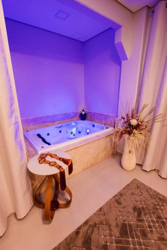 a bathroom with a tub with purple walls and a table at Hotel Golden Palace in Fonte Termal Água Quente