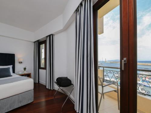 a bedroom with a bed and a view of the ocean at Porto Veneziano Hotel in Chania