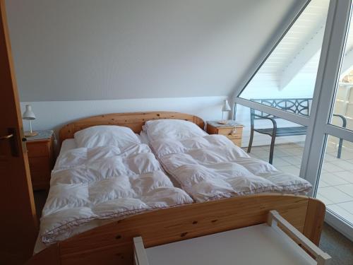 a bed with white sheets on it in a room at Haus am Prerow-Strand in Prerow