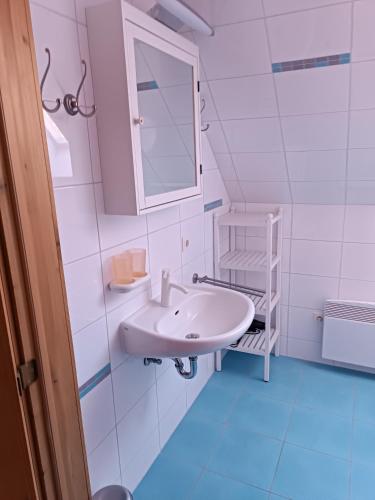 a white bathroom with a sink and a mirror at Haus am Prerow-Strand in Prerow